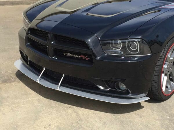 A black Dodge Charger R/T sports car parked in a lot, showcasing its front grille and headlights.