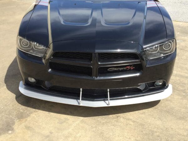 A black Dodge Charger R/T parked in a parking lot, showcasing its front grille and headlights.