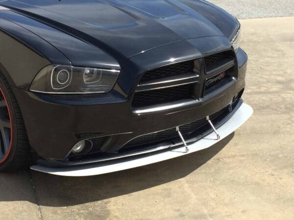 A black Dodge Charger parked in a lot, featuring a prominent front grille and sleek headlights.