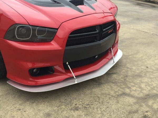 A red Dodge Charger SRT with a front splitter parked in a lot.
