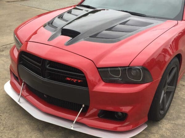 A red sports car featuring a black hood and "SRT" logo on the front grille.