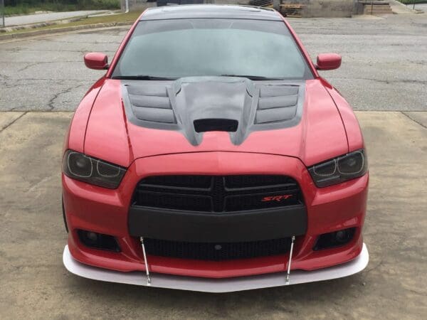 A red sports car with a black hood and "SRT" badge parked in a lot.