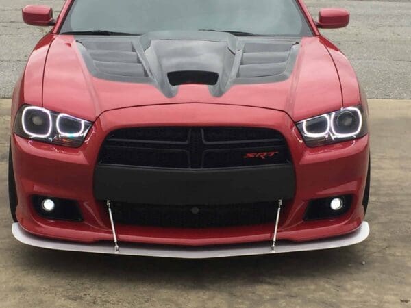 The front view of a red Dodge Charger SRT with distinctive headlights and a vented hood.