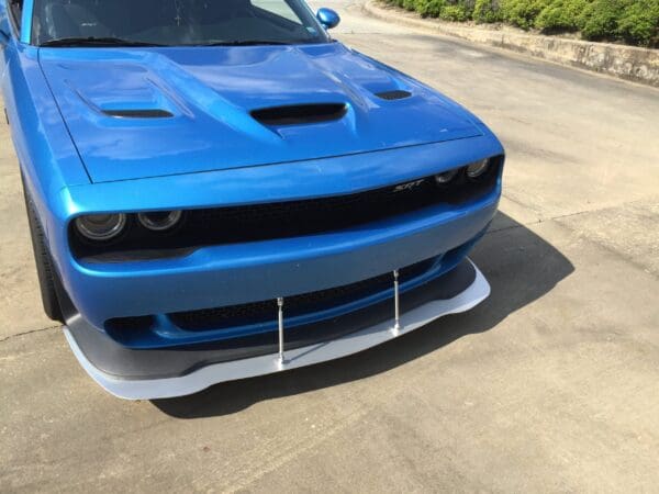 A blue Dodge Challenger SRT parked in a lot, featuring a front splitter and hood vents.