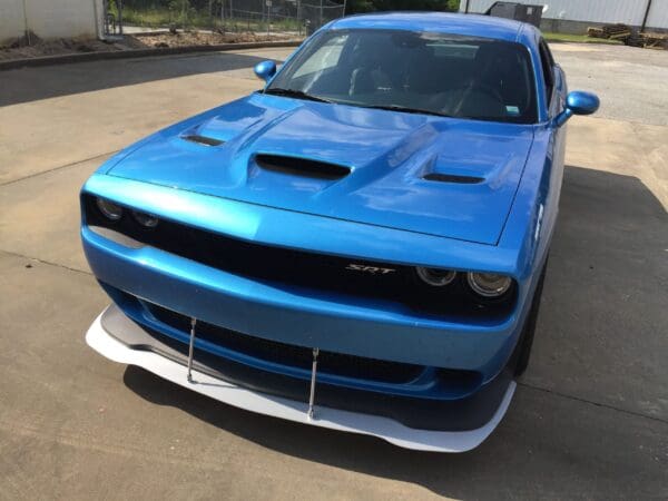 A blue Dodge Charger SRT parked in a lot, viewed from the front, showing its sleek design and distinctive grille.