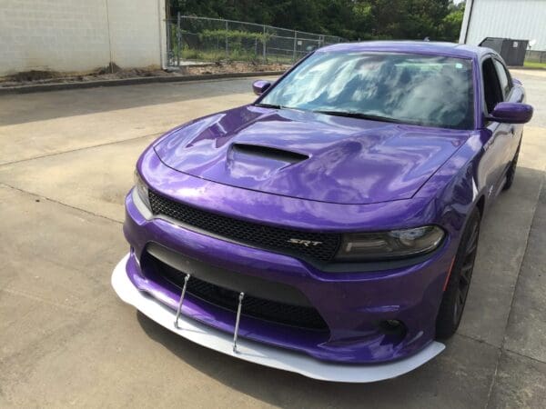A purple car parked in a driveway beside a building.