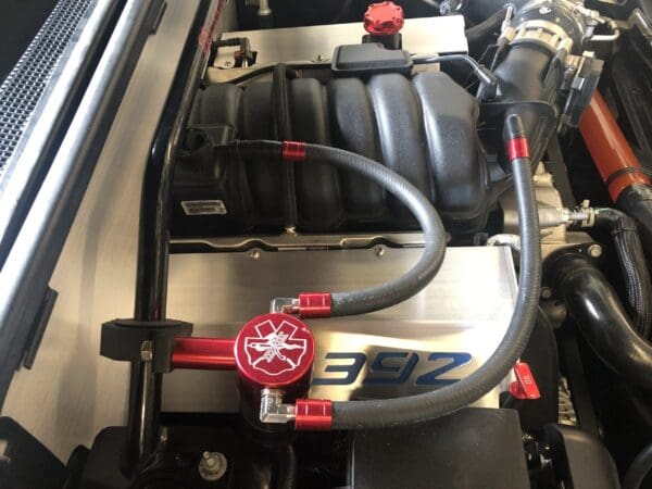 Close-up of a car engine featuring a "392" label, red accents, and detailed components.