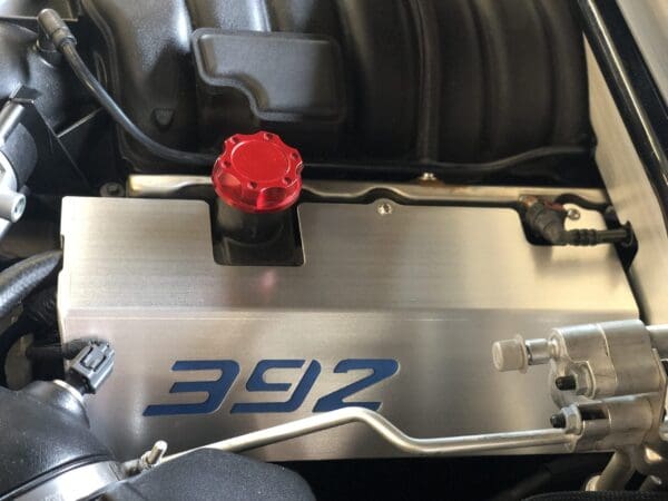 Close-up of a car engine featuring a red cap and "392" in blue on a metal cover.