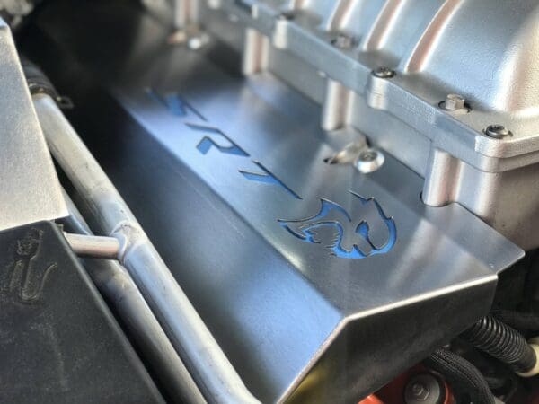 Close-up of a car engine featuring the SRT logo and a stylized emblem etched on a metal cover.