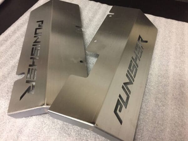 Metal object with "PUNISHER" engraved, placed on a textured surface.