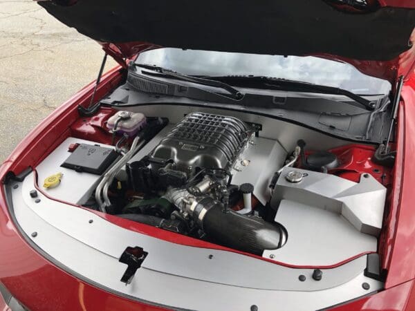 The engine compartment of a red sports car, showcasing a powerful engine with a sleek, organized layout.