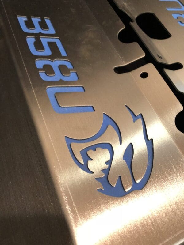Blue logo on metal surface with stylized flame and face profile within the letters "358U."