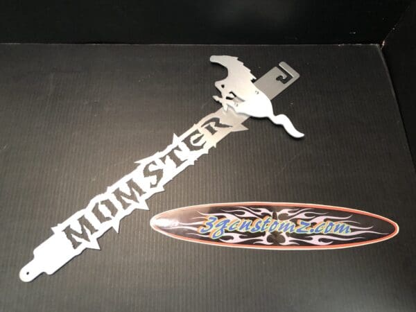 A metal hood prop with the word MOMSTER