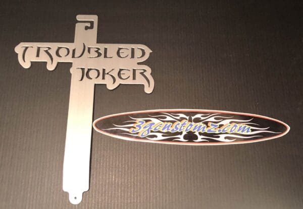 A metal hood prop with the word TROUBLED JOKER