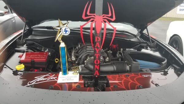 Car engine with a trophy and another trohpy that has a "Daytona" text, and red spider decoration.