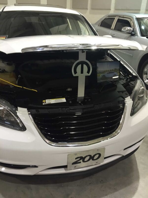 A white car with the hood open in a garage