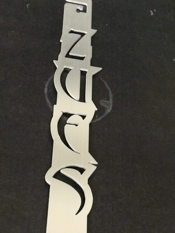Silver vertical piece with intricate cut-out design on a black background.