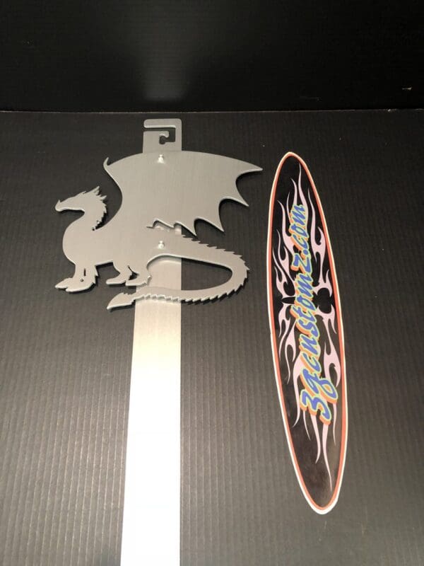 Metal dragon silhouette and colorful skateboard sticker on black surface.