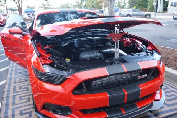 A red and black mustang parked on the side of a road