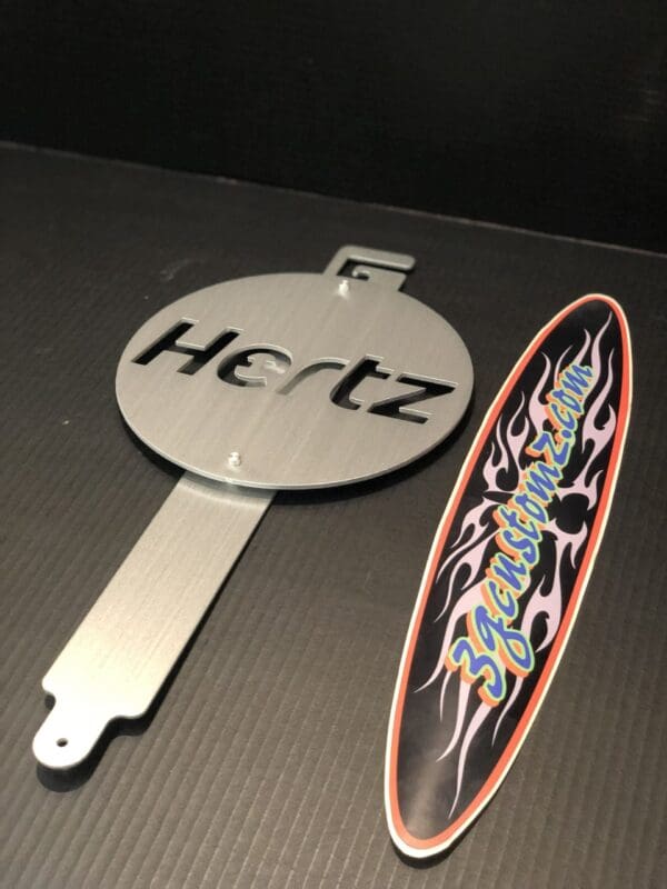 Metallic hood prop with the text "Hertz" and a colorful sticker with flame design.