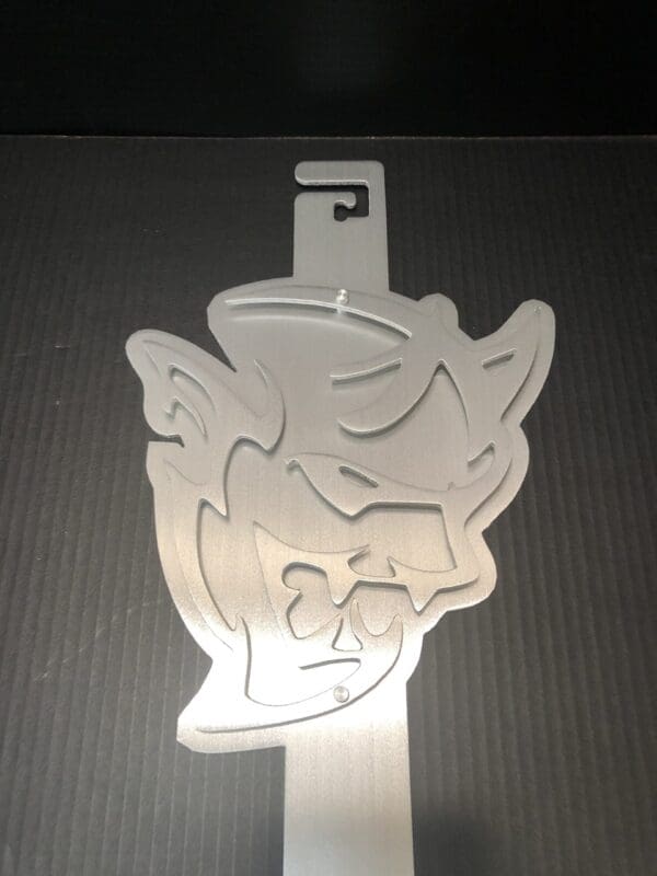 Silver cut-out of a cartoon character's face on a dark background.