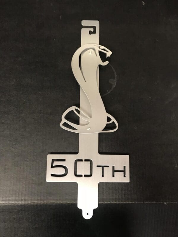 Metallic Hood Prop with "50th" inscription and a decorative element.
