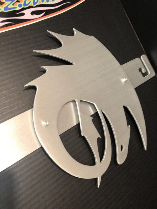 Silver emblem with a stylized flame design on a textured black background.
