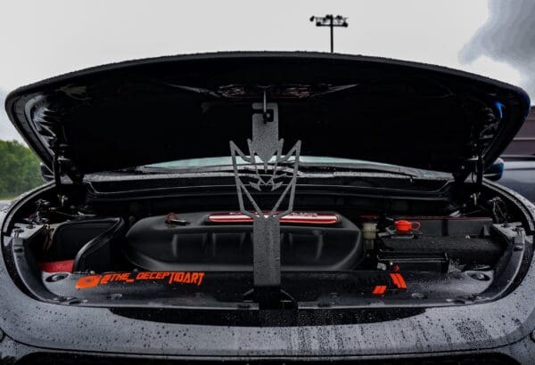 An orange car with its hood open in a parking lot