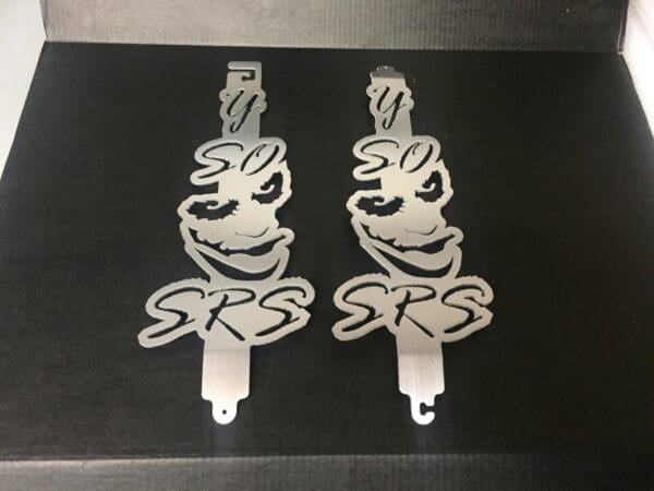 2 metal hood prop with the word Y SO SERIOUS and a joker head