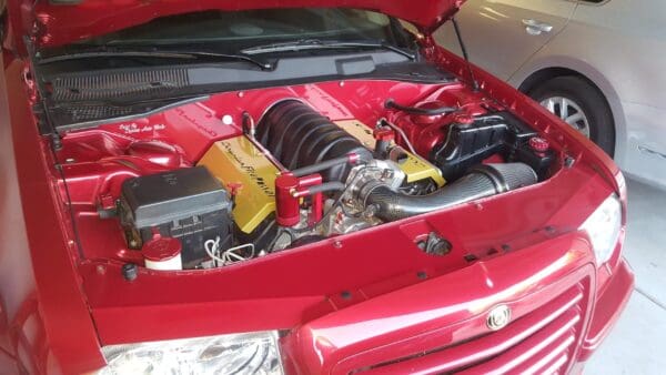 A red car with its hood open, revealing a detailed engine.