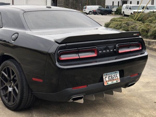 A black Dodge car with Georgia license plate CJG8655 parked in a lot, showcasing its rear design and taillights.