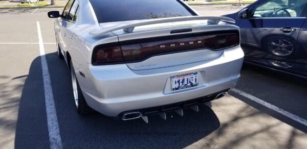 Two cars parked side by side in a parking lot, featuring a Dodge Charger with a California license plate.