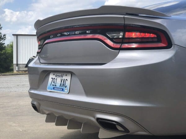 The rear of a silver Dodge Charger with Kentucky plate 791-XAC, parked in a lot near a white building.