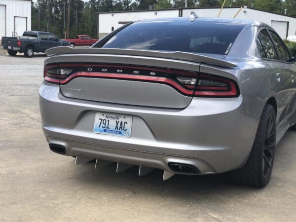 A silver Dodge Charger with a Kentucky license plate, 791 XAC, parked in a lot near industrial buildings.