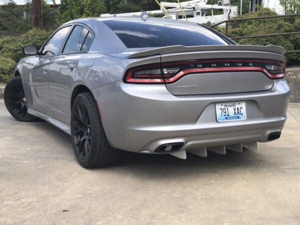A silver Dodge Charger with Kentucky plates, parked in a driveway, showcasing its rear design and black wheels.