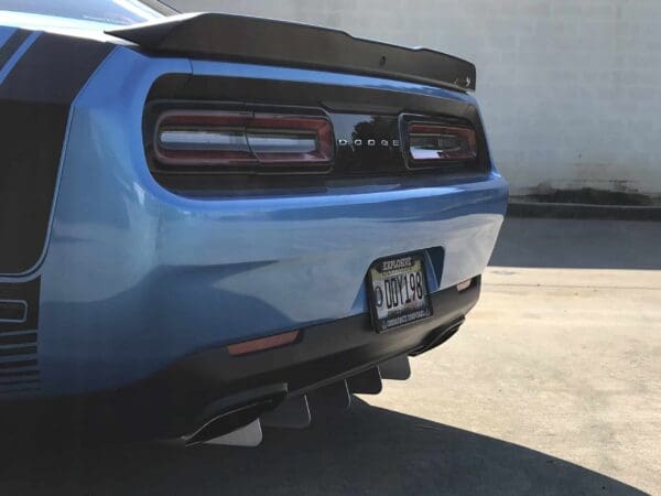 A blue Dodge sports car parked in a lot, showing its rear with a license plate reading "DDY198."