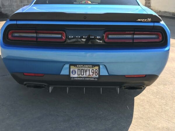 The rear of a blue Dodge SRT car with a license plate reading "DDY198" is parked in a driveway.