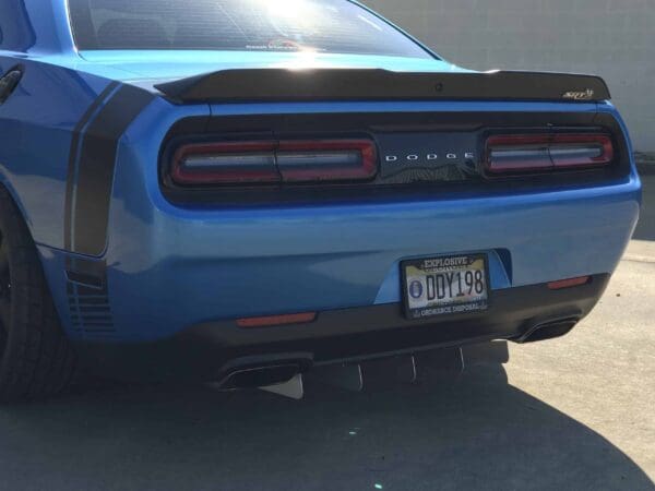 A blue Dodge SRT parked in a lot, featuring a visible license plate: DDY198, with "Explosive Ordnance Disposal" text.