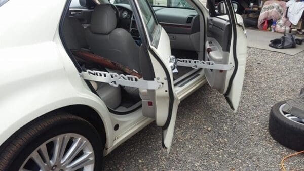 A white car with its door open and a tire on the ground