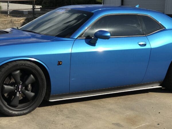 A blue sports car with tinted windows and black wheels parked in a driveway.