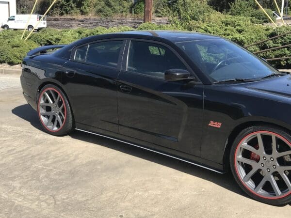 A black sports car with red-trimmed wheels is parked in a parking lot.