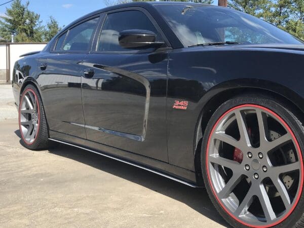 A black sports car with "345 HEMI" badge, parked in a lot, featuring silver rims with red accents.