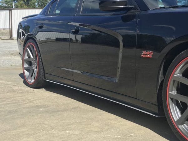 A black sports car, featuring a "345 HEMI" badge and red-trimmed wheels, parked in a lot.
