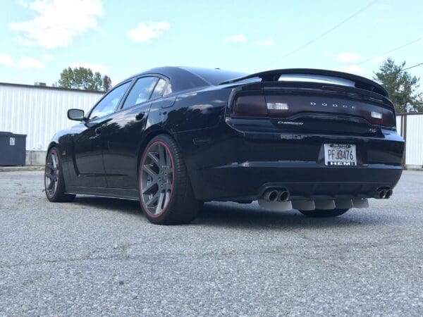 A black Dodge Charger R/T with gray rims parked in a parking lot, license plate PFJ3476 HEMI visible.
