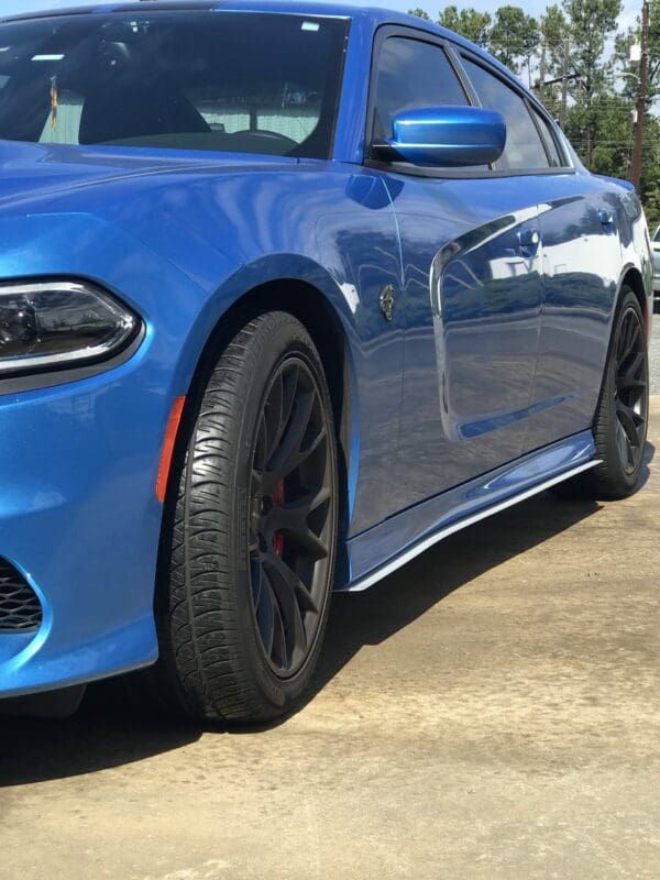 A blue Dodge Charger parked in a lot, showcasing its sleek design and black wheels.