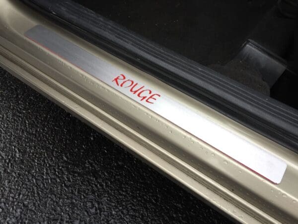 The word ROUGE engraves on a car door