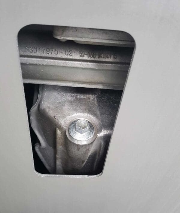 Close-up of a metal object with a hole, showing a bolt and engraved numbers: 38017975-02 52-068-BK100715.