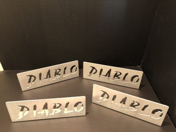 Four metallic signs displaying the word "DIABLO" with a rugged font against a dark background.