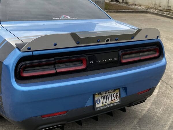 The rear end of a blue car parked in a parking lot