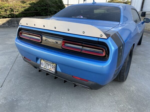 The rear end of a blue car parked in a driveway